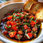 Fresh tomato and basil bruschetta dip in a white bowl with toasted baguette slices.