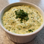 Creamy salsa verde queso dip topped with fresh cilantro in a white bowl.