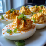 Spicy chili garlic deviled eggs topped with red chili powder and fresh green onions.