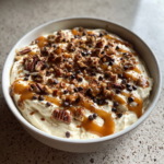 Creamy turtle cheesecake dip topped with caramel sauce, pecans, and mini chocolate chips.