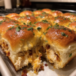 Cheesy pull-apart Crack Chicken Sliders with melted cheese and bacon on a baking sheet.