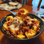 Hearty meat lovers tortellini pasta with savory meat sauce and a melted cheese pull.