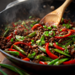Sizzling Chinese ground beef stir fry with snap peas and red peppers in a wok.