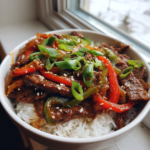 Beef and pepper rice bowl with bell peppers, green onions, and sesame seeds.