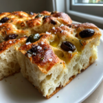 Slices of freshly baked olive focaccia bread with black olives, sea salt, and herbs.