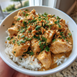 Creamy Thai peanut chicken over white rice topped with crushed peanuts and fresh cilantro.