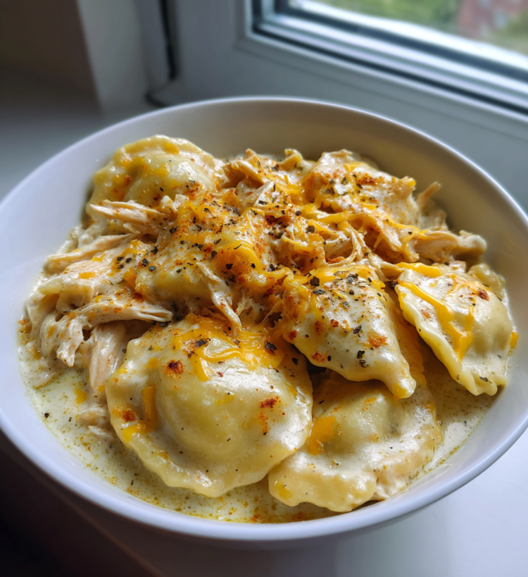A bowl of creamy Crock Pot chicken pierogi stew topped with melted cheese and spices.